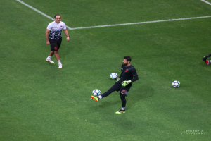 Ein Mann in einem Sportoutfit kickt einen Fußball auf einem saftig grünen Feld.