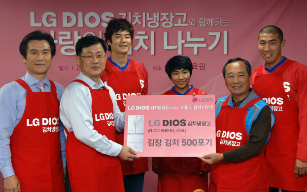 Eine Gruppe von Männern, die eine große LG-Firmenkarte halten, mit einem Banner im Hintergrund.