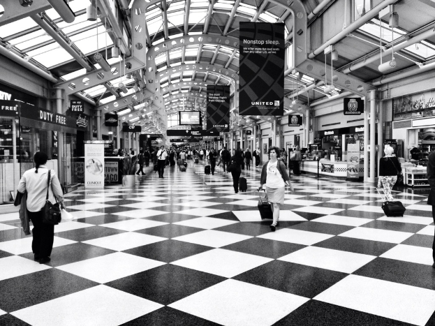 Menschen mit Taschen gehen in einem Gebäude mit Geschäften und Bannern auf der Seite.