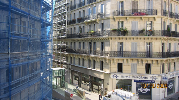 Ein großes Gebäude im Bau auf der linken Seite, mit einem Geschäft auf der rechten Seite unten.