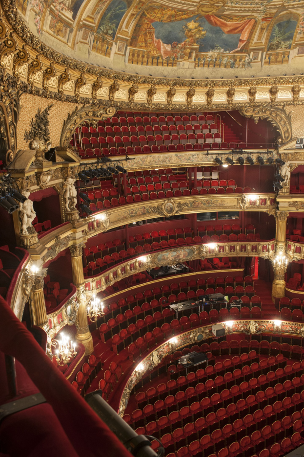 Innenansicht des Auditoriums der Königlichen Oper in London mit Sitzreihen, verzierten Geländern, Säulen, Leuchten, Wandskulpturen und einer Deckenmalerei.