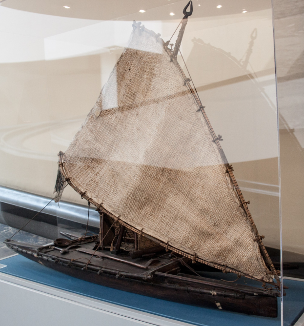 Ein Modellsegelboot mit geschwellten Segeln, das in einer Glasvitrine ausgestellt ist und an einer Wand mit Deckenbeleuchtung steht.